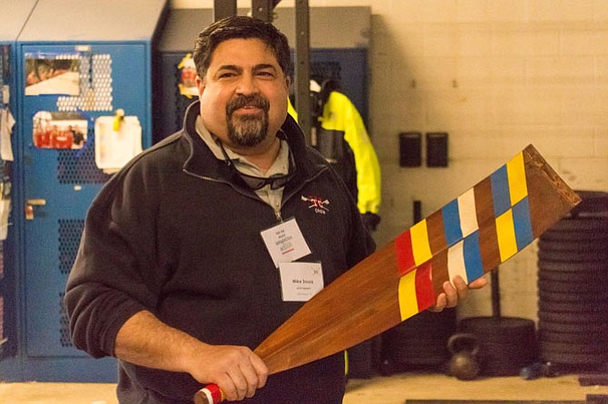 Alexandria Crew Boosters President Michael Souza holds a ceremonial oar presented by the 1971 TC Williams Crew Team.