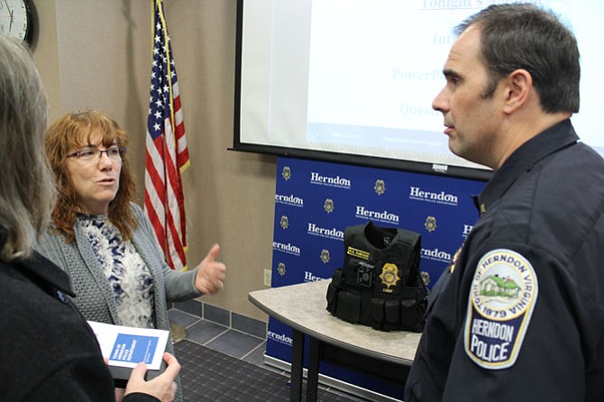 Town of Herndon resident Lorna Schmid and her husband David Boldt ask Lt. Steve Thompson of the Herndon Police Department questions about how the officers will be using the cameras. The model of camera that will be used, a Panasonic Arbitrator Body Worn Camera, was on display and will be worn by officers on their vests.