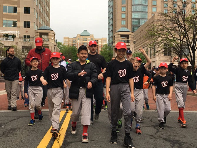 Reston-Herndon Little League (RHLL) players march in a parade in Reston Town Center on Saturday, April 22. Pictured here, AA TAG Muay Thai AL Nationals with their coach Brian Dougherty.