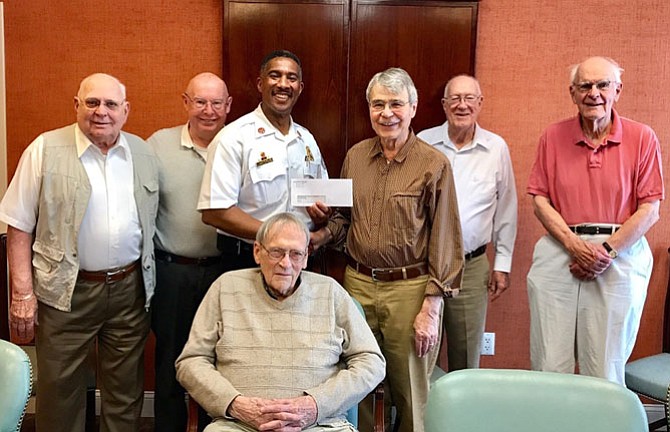 Members of the Goodwin House Alexandria Chapel Outreach Committee present a check for $2,000 April 15 to Firefighters and Friends founder Will Bailey. “This will help us do even more for the thousands of children we help every year,” said Bailey, who is a Fairfax County Fire and Rescue Department Battalion Chief. From left are Ed Morai, the Rev. Dr. Frank Wade, Will Bailey, Dan Kelley (seated), Pierre Shostal, Admiral (Ret.) Mike McCaffree and Roger Brown.
