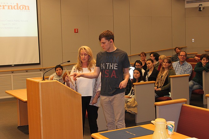 Elizabeth Vosseller, director of the Growing Kids Therapy Center, helps one of her Autistic students testify during the Herndon Town Council meeting by using a letter board. This is an instrument that allows users to communicate by pointing and spelling out their message.