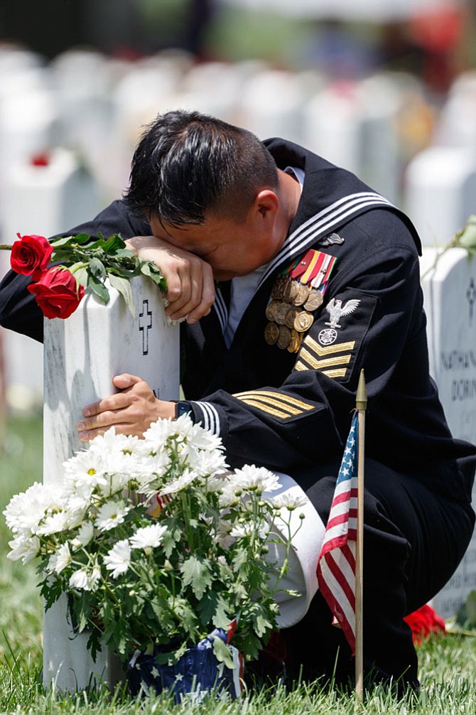 A service member weeps at the grave of a fallen comrade in Section 60 of Arlington National Cemetery following the Memorial Day Observance ceremony May 29.