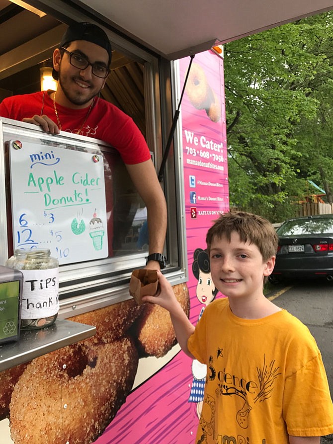 Finn Ballew, 11, of Vienna takes his donut purchase from Iessa Gammo, an employee of Mama’s Donut Bites at the Vienna Farmers Market. The donuts are one of Ballew’s favorite items at the market.