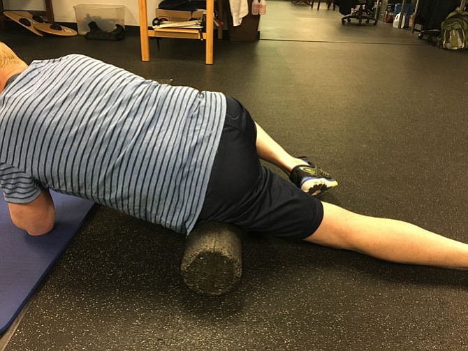 Geoff Robison of Custom Kinetics in McLean uses a foam roller to help a client recover from an injury.
