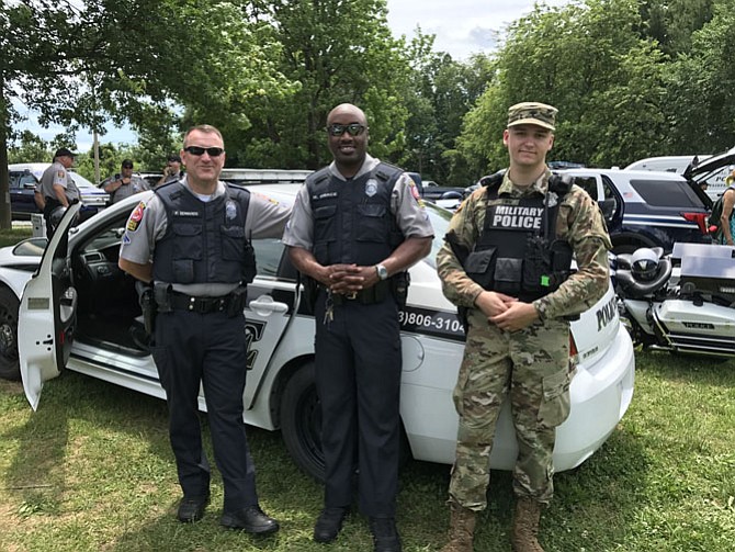 From left: Officers P. Edwards and M. Grace and Military Police Specialist Seth Brown stand near the line up of military and police cars eager to answer questions from the local community. 