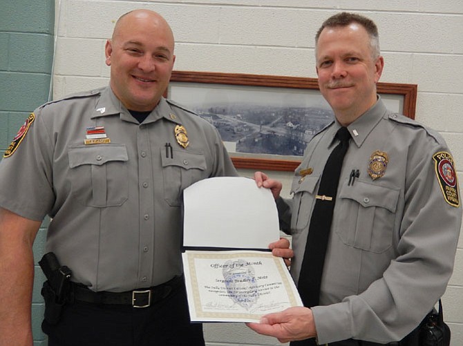 Police Sgt. Brad Metz (on left) receives his Officer of the Month certificate from the Sully District Station’s assistant commander, Lt. Alan Hanson.