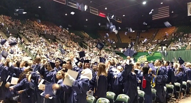 Students toss their caps in the air upon officially graduating from Woodson High School.
