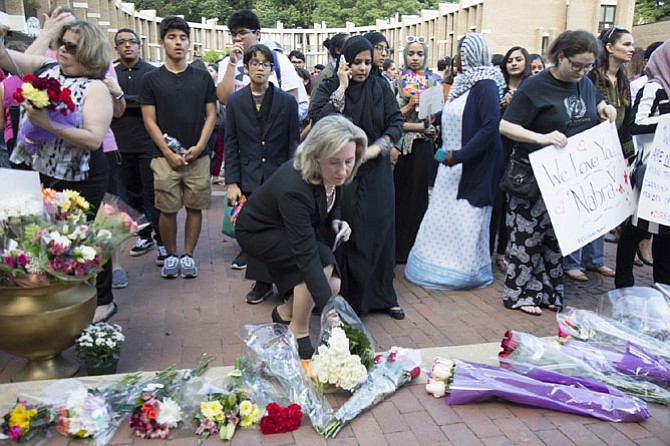 U.S. Rep. Barbara Comstock (R-10) placed a bouquet of white roses on the stage at Lake Anne Plaza during the vigil for Nabra before she gestured the sign of the cross.
