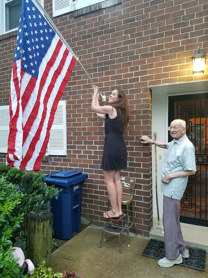 Dick Cohen, a 90-year-old decorated World War II veteran, gets help from a neighbor replacing the U.S. flag that was burned on the pole outside his door over the Fourth of July  weekend. Several flag desecrations, thefts and burnings have taken place recently in the West End townhouse community of Westridge. In a show of solidarity and support, the Seminary West Civic Association, which includes Westridge, has declared Saturday, July 15, as Neighborhood Flag Day. Residents across the city are encouraged to participate.
