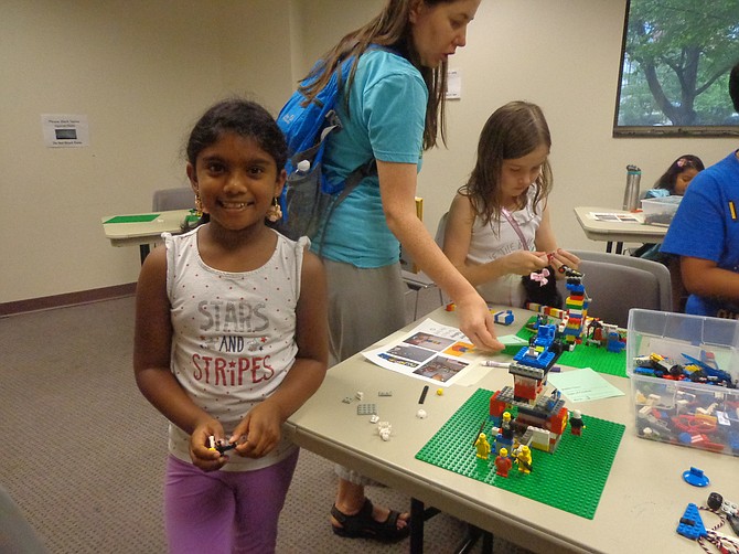 Seven-year-old Prisha Neelapala smiles for the camera while attending Lego Club, which gathered at Herndon Fortnightly Library on July 14.