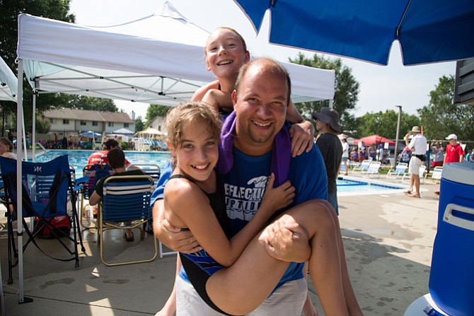 Dylan Evans, 38, works at Parks and Recreation of Loudoun County. He coaches the Reflection Riptides and is pictured here holding 11-year-old swimmers, sixth graders Grace Dowell and Caitlyn Allain.