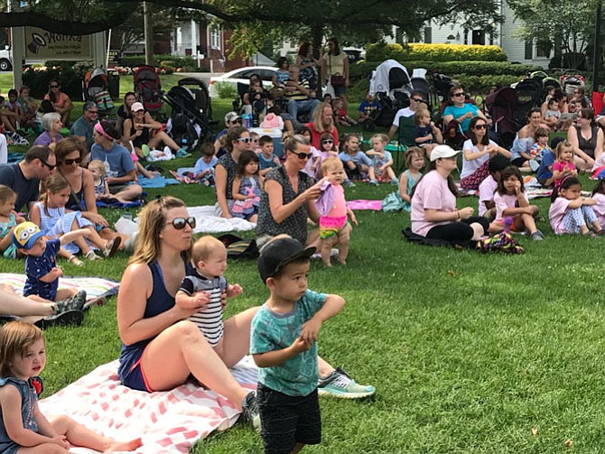 Chrissy Chevalier holds up her son, Brody, 5 months old, while daughter, Lexi, 3 (left) cools her tootsies as they watched Groovy Nate at Farmers' Market Fun Day on Thursday, July 27. The hot weather didn't stop Tyler Wilson 2, (front) from dancing to the music.