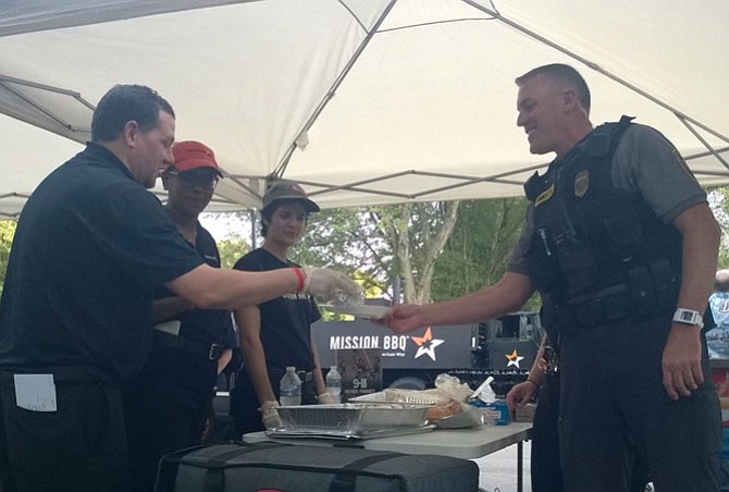 Mission BBQ General Manager Michael Ordonez and catering staff Amy Galloway, Nina Dalal and Victoria Everhart give a pulled chicken slider sandwich to Lt. Timothy Forrest Aug. 1 at a National Night Out block party in the Franconia Police District. “Our mission is to serve and serve those who serve,” Ordonez said.