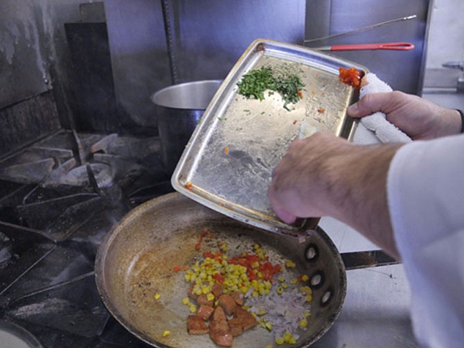 Seasonal vegetables and Andouille added to pan of mixed oil.