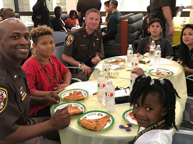 1st Lt. Jamal Perkins, Le Bron, 12, 2nd Lt. Shaun Timothy, Josh, 9, Katia Brizuela of Fairfax County Federal Credit Union, and Ja'Kayla, 5, enjoy a pizza party at the Fairfax County Courthouse Atrium Cafe.
