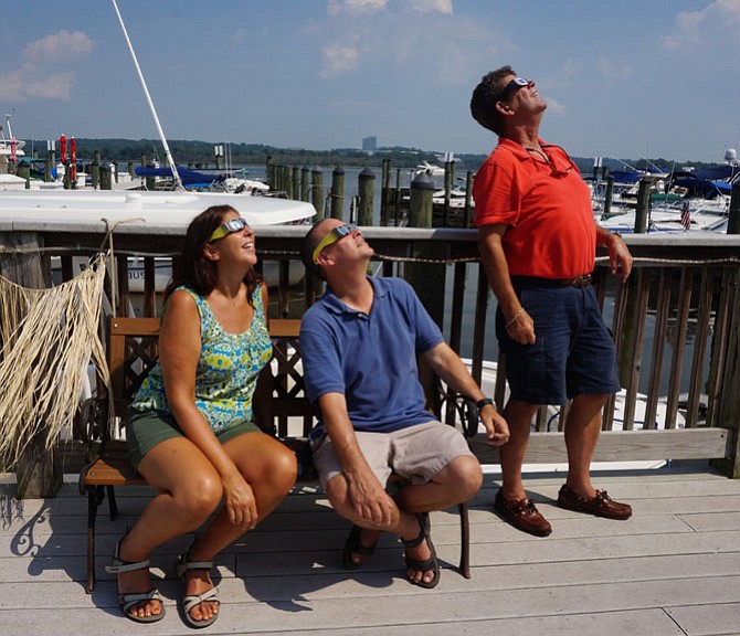 Elle and Richard Tauber join Jeff Carpenter in watching the solar eclipse Aug. 21 along the Alexandria waterfront.