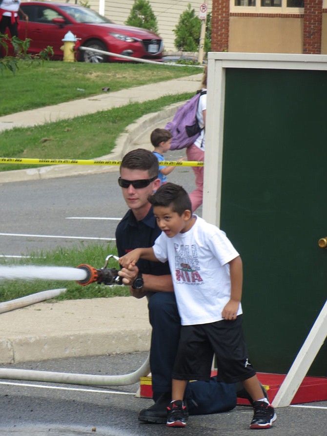Probationary Firefighter Tristan Plant (left) helps Jake Lopez spray down fire targets with a hose during the annual Arlington Police, Fire, Sheriff Block Party outside Kenmore Middle School on Aug. 27.
