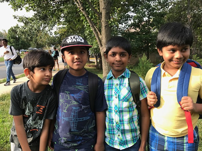 From left: Friends Nikhil Damera, Shamith Madhusudana, and Saketh Ravilla make their ages clear. "I'm not six years old. I'm six and a half, " the boys each say when asked their age. The children team up their friend, Krish Kandimalla, 8, for a group photo at their bus stop in the Town of Herndon. 

