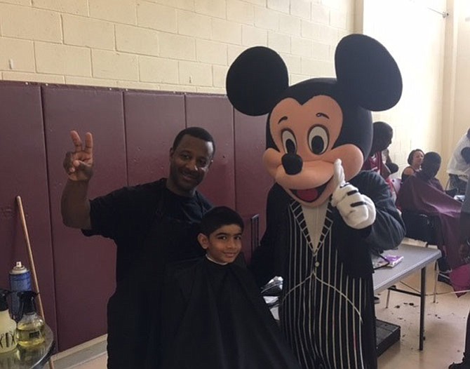 Marvin the barber and Mickey Mouse prepares to give a child a haircut Aug. 27 at Charles Houston Recreation Center.
