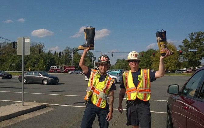 Fairfax County Fire and Rescue Master Technician Johnathan Macquilliam and Capt. Matthew C. Burns hold their boots high as they work a Labor Day crowd of generous motorists at a Fairfax traffic signal on Waples Mill Road and U.S. Route 50. They helped their Station 21 in Fair Oaks raise $14,200.12 in just four days, Sept. 1-4, for MDA Greater Washington, D.C., and the International Association of Firefighters disaster relief fund.