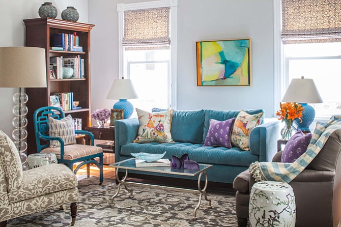 In this room by Susan Nelson of Home on Cameron, the soft gray and lavender tones provide a backdrop for the brightly colored sofa and accessories.