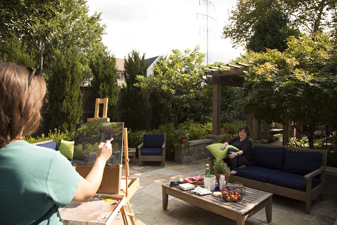 Chantilly-based multimedia artist Lorrie Herman paints an oil painting of Signe and Paul Friedrichs’ backyard garden during the tour. Signe’s favorite spot in the garden is her outdoor couch.