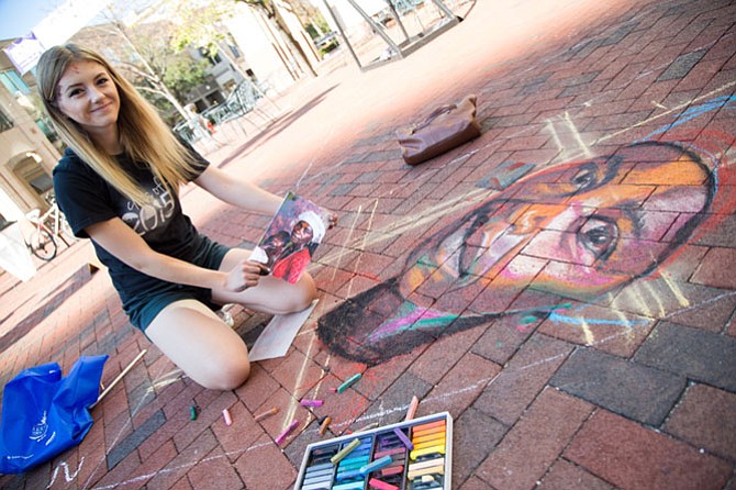 Abigail Lockhart, an art student at Shepherd University, draws a chalk mural in a professional space at ChalkFest Saturday in Reston Town Center.