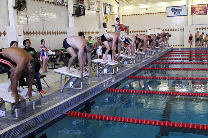 Swimmers take their starting positions on the blocks for the second heat of the 100 yard freestyle.