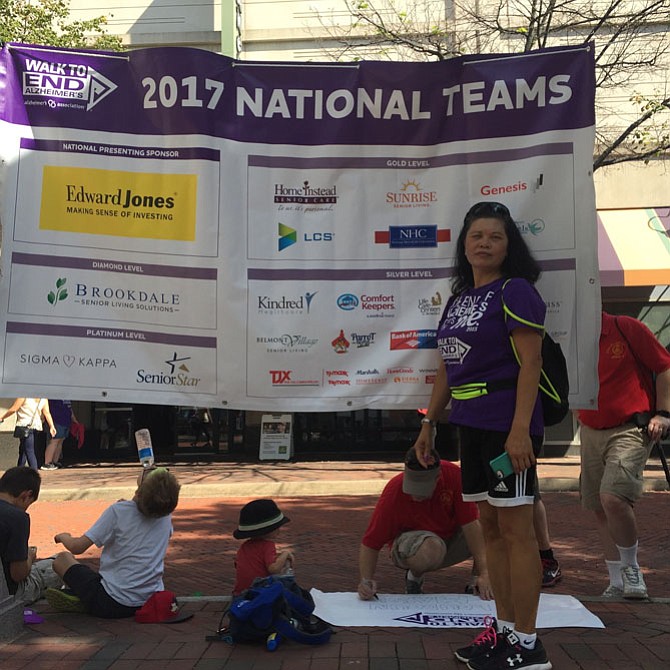 Jocelyn Herradura, a Sunrise Senior Living caregiver, stands in front of the sponsors for the Alzheimer's Walk.