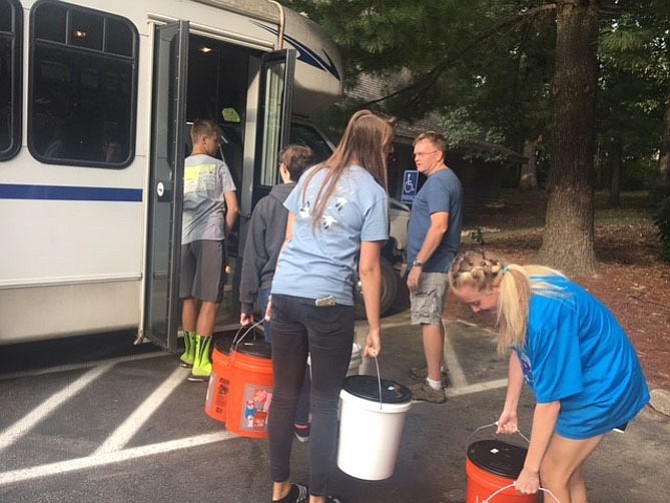 Youth group volunteer Scott Tennent supervises teenagers of the Burke United Methodist Church youth group as they load cleaning kits onto the church van Sept. 17 before these disaster relief supplies were hauled all the way toward Richmond two days later. 