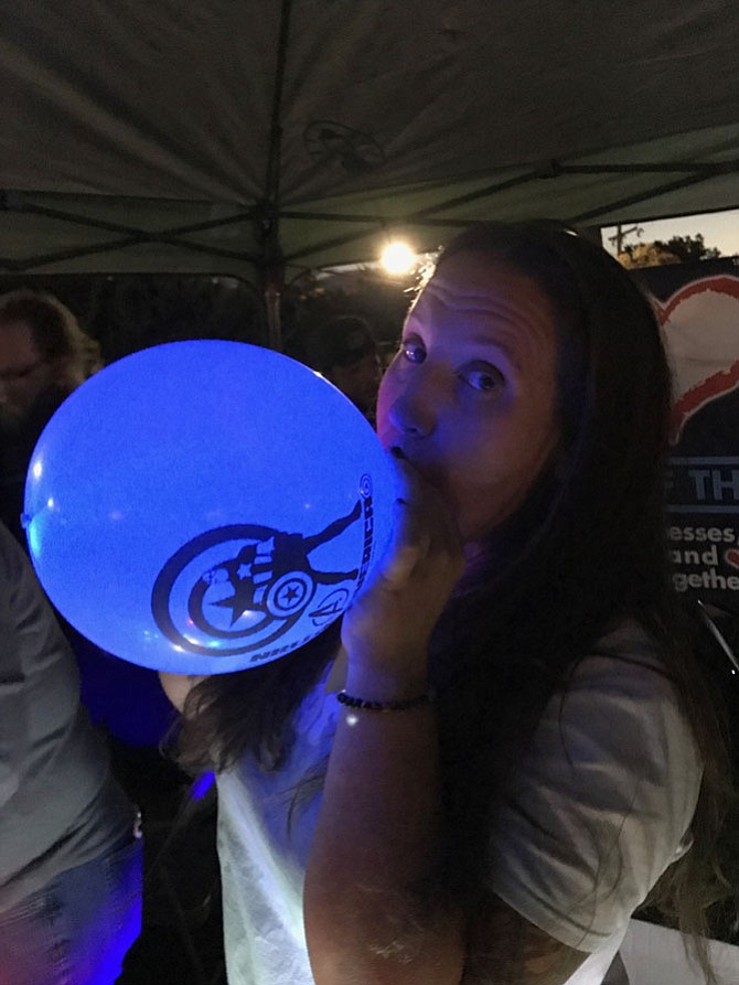 Stephanie Wright is a member of the nonprofit organization Eye of the Heart (EOTH) that assisted with the JamBrew's weekly production needs. Wright blows up an LED balloon for a concertgoer at the Friday, Sept. 29 concert. EOTH is known for bringing businesses, community, and nonprofits together. 
