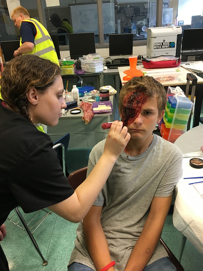 Gavin Nielsen of North Bethesda is made up by Joelle Miller to simulate a person suffering a gunshot wound in the eye for the mass casualty drill at Whitman High School on Sunday.