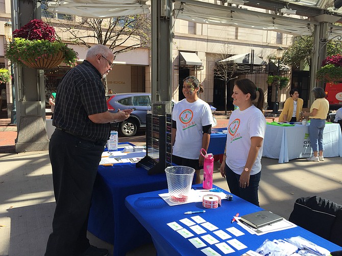 Elizabeth Darak of Dallas and Karla Nativi of Fairfax let Mike Hanley of Ashburn roll the dice for a prize.
