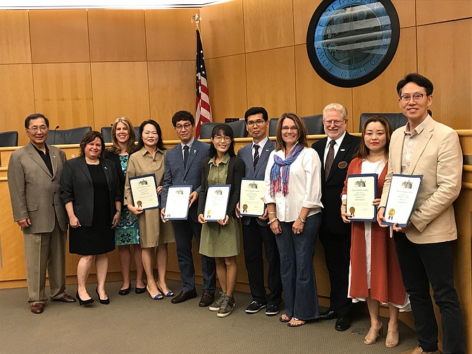 From left: Heyon Kon Lee, president and founder of Grandmaster H.K. Lee Academy of TaeKwonDo; Signe Friedrichs, Herndon Town Councilmember; Herndon Vice Mayor Jennifer K. Baker; SeonSoon Shin; Grandmaster SangGeun Lee, MARUHAN CHEONGMU TAEKWONDO, Member of the Executive Board of Directors for the Sacheon City TKD Association; MinSun Hong; Grandmaster GiJin Lee, MARUHAN UIRYEOUNG TAEKWONDO, Member of the Board of Directors for the KyungSangNam-do Province; Herndon Mayor Lisa C. Merkel; Herndon Councilmember Jeffrey L. Davidson; WonKeong Na; and Grandmaster HanSeong Choi, MARUHAN AJU TAEKWONDO, member of the Board of Directors for the GeoJei City, TKD Association; pose together in the Herndon Town Council Chambers after the mayor and town councilmembers and the visiting South Koreans exchanged gifts and certification.