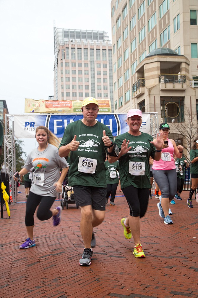 Racers run out of the starting gate at the Reston Pumpkin 5K Race at Reston Town Center Sunday morning, Oct. 8.