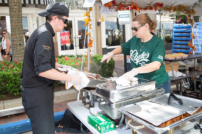 Sam Martin, sous-chef at Clyde's of Reston, helps Shannon Johnson, bookkeeper at Clyde's of Reston unload brats for the attendees at the Taste of Fall Festival in Reston Town Center Saturday, Oct. 7.