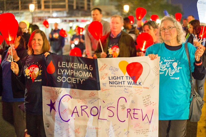 Carol Kasson (right) and her friend Paula Kone, a Burke resident, carried a banner that said, “Carol’s Crew,” at the Light the Night walk for Leukemia Friday night in Reston Town Center. Kasson is a cancer survivor. 