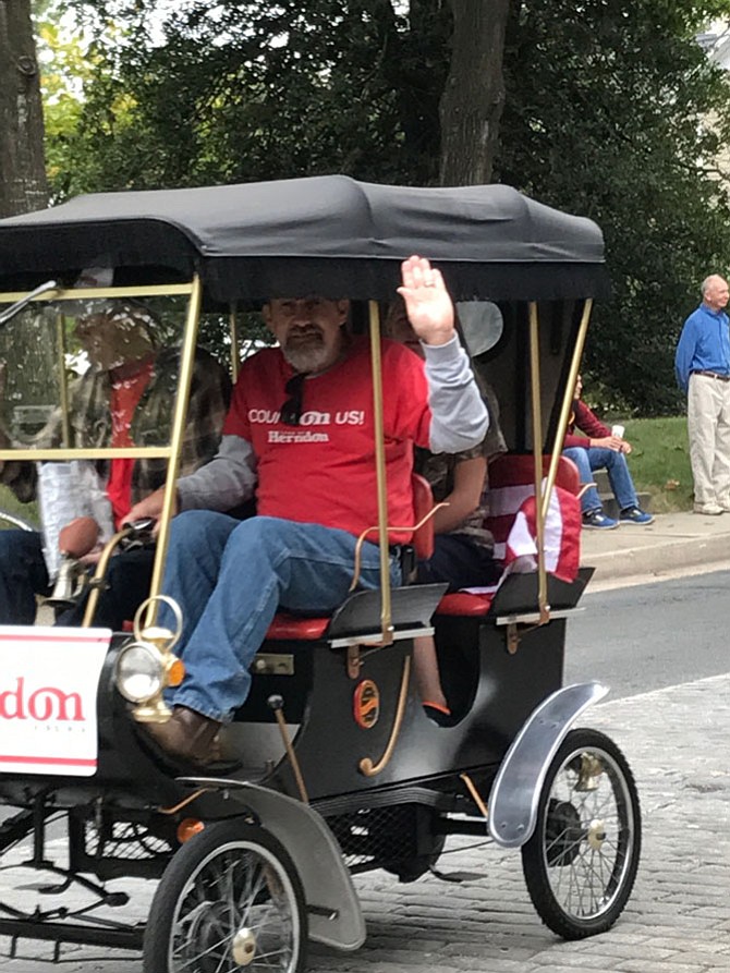 The smallest car in the Herndon Homecoming Parade 2017 belonged to Dusty Simmons and Daryl Crocker. Simmons gives a big wave to parade viewers as Crocker, a retired Town of Herndon employee, sits beside him. 