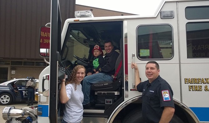 From left: Kelly Burns of Sterling holds open the driver side door as Fairfax toddler Patrick Vetterick and his dad, Paul, sit behind the wheel of the fire engine Saturday, while Fairfax County Fire and Rescue Tech. Brian Talbot holds down his truck. “I’ve been driving fire engines for 23 years,” Talbot says. This annual open house is not Burns’ first rodeo, either. The 16-year-old volunteers in the fire house run by her dad, Capt. Matt Burns.