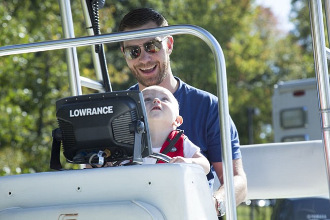Patrick Dunn of Reston sits with his son Lincoln, 1, at the helm of a boat used by the Fairfax County Police Department Special Operations Division Underwater Search and Recovery Unit during the open house.