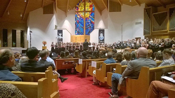 Madrigals and select singers from a local high school help the Vienna Choral Society end their concert Saturday night on a positive note with a cheerful Harry Belafonte and Robert Freedman song “Turn the World Around.” Their “Surround Sound” concert kicked off their 30th season Oct. 21 in the circular sanctuary of Vienna Baptist Church at 541 Marshall Road, S.W. Students from the James Madison High School chorus and chamber orchestra were guest artists. Concert pianist is retired music educator Melvin Goodwyn.
