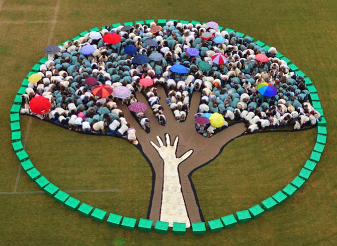 People in different-colored T-shirts crouched down to create this year’s Complete the Circle artwork.