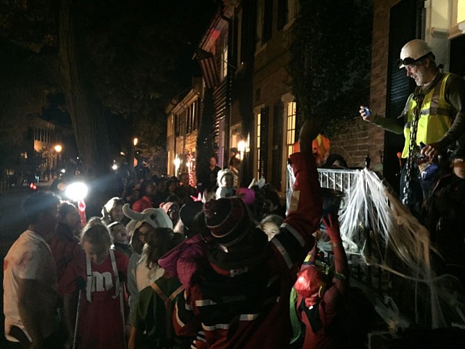 Chris Leary, a phantom construction worker, gives out candy to a crowd of trick-or-treaters.