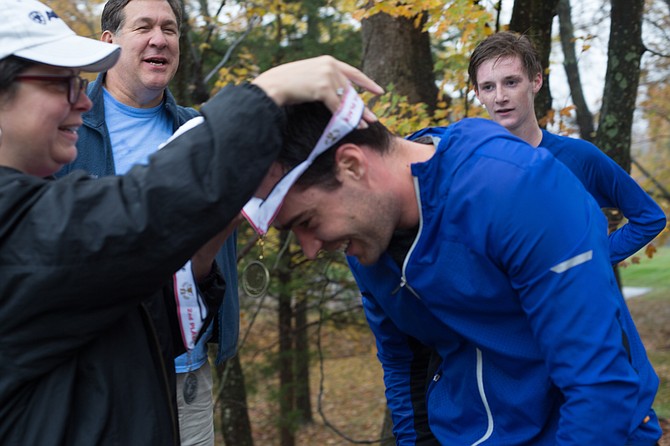 Donna Zimmerman, member of the board for Lift Me Up, gives Wiehan Peyper, 31, of Great Falls a medal for winning first place in the Great Falls Lift Me Up 5K Sunday morning, Nov. 5. 
