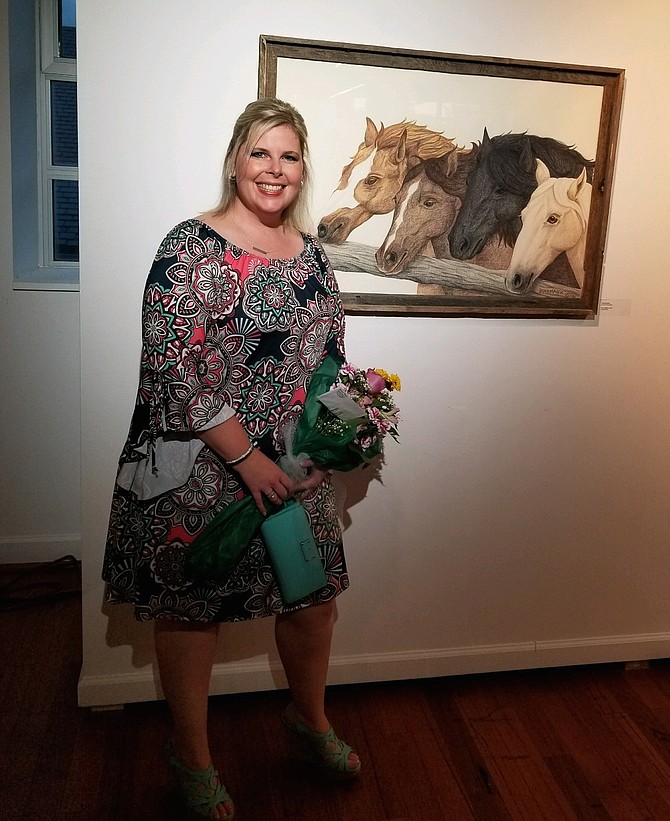 Ashley Birkmaier at the McGuire Woods Gallery, Workhouse Arts Center, next to her artwork made with Prismacolor pencils.