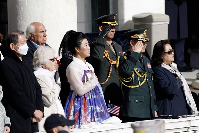 Michelle WinSook, center, of the Korean War Women’s Veterans Association, places her hand over her heart during the singing of the U.S. National Anthem at the Veterans Day ceremony at Arlington National Cemetery.  This year’s ceremony gave special recognition to Korean War veterans.