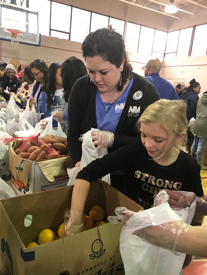 Amber Gallmetzer of Northwest Federal Credit Union in Herndon and her daughter Brianna Runyon help pack sweet potatoes and oranges as part of the 8th Annual Northern Virginia Project Giveback Thanksgiving meals for families in need. 
