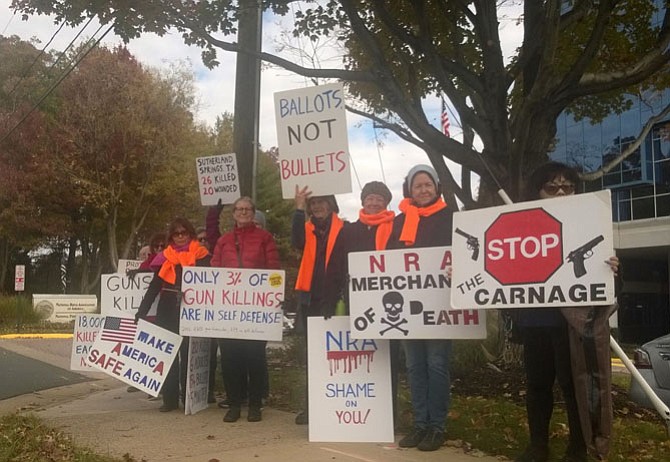 Activists against gun violence line the sidewalk Nov. 14 in front of the headquarters of the National Rifle Association at 11250 Waples Mill Road in Fairfax, where they hold protest signs for passing motorists as part of their awareness campaign. This regular gathering is an open-action protest and signs are provided to those who want to participate on the 14th of each month.