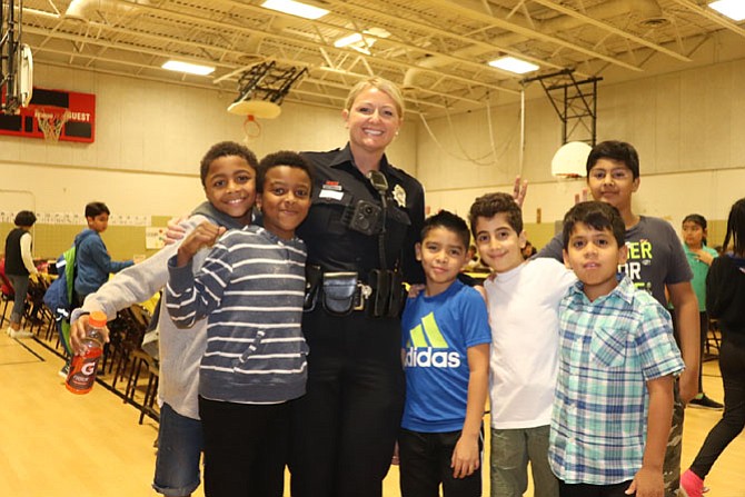 Crime Prevention Specialist SPO Denise Randles poses with students at Herndon Elementary School's Thanksgiving Feast.