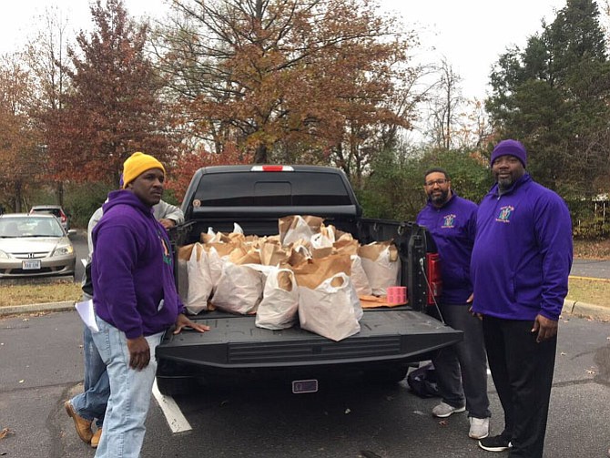 Members of the Sigma Mu Mu Chapter of Omega PSI Phi Fraternity, Incorporated, Reginald Parker, Marc Byer (hidden), Eric Martin, and Paul Forbes unload groceries for LINK's Thanksgiving Holiday Program. 